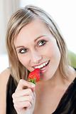 Smiling woman eating a strawberry 