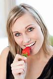 Radiant woman eating a strawberry 
