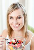 Cheerful woman eating a fruit salad 