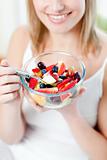 Blond woman eating a fruit salad 