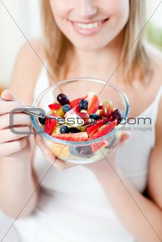 Blond woman eating a fruit salad 