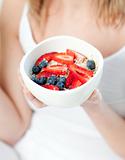 Blond woman holding a bowl of muesli with fruits 