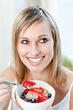 Delighted woman eating muesli with fruits 