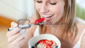 Charming woman eating muesli with fruits 