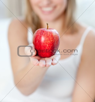 Close-up of a blond woman showing an apple