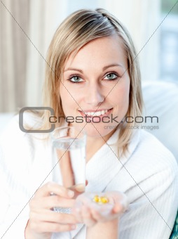 Sick caucasian woman holding a glass of water and pills