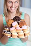 Blond woman holding a plate of cakes at home