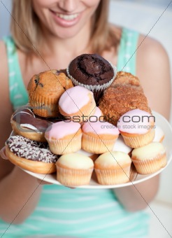 Blond woman holding a plate of cakes