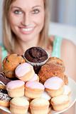 Blond woman holding a plate of cakes at home