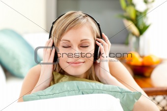 Relaxed blond woman listening music lying on a sofa 