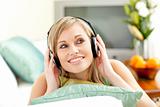 Charming blond woman listening music lying on a sofa