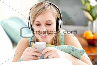 Smiling blond woman listening music lying on a sofa 