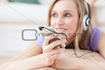Blond woman listening music lying on the floor