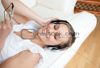 Relaxed young woman listening music lying on a sofa