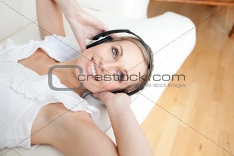 Bright young woman listening music lying on a sofa 