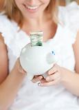 Blond woman saving money in a piggy-bank 
