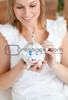 Charming woman saving money in a piggy-bank 