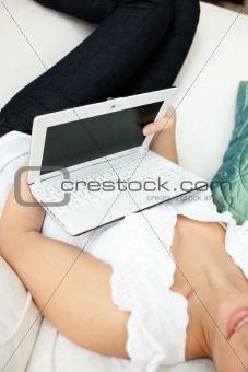 Caucasian woman surfing the internet lying on a sofa 