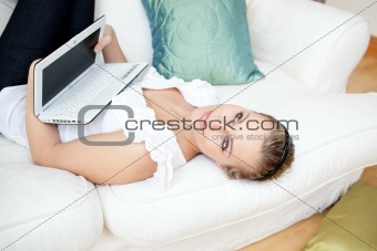 Attractive young woman surfing the internet lying on a sofa 