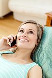 Jolly woman talking on phone lying on a sofa at home