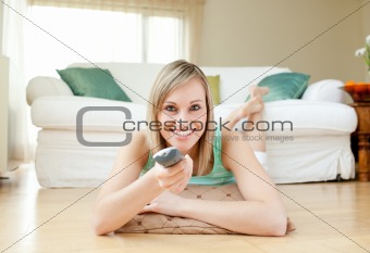 Young woman watching TV lying on the floor 