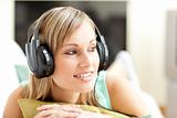 Beautful young woman listening music lying on a sofa 