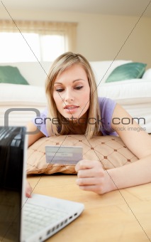 Attractive woman shopping on-line lying on the floor