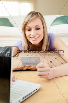 Smiling woman shopping on-line lying on the floor 