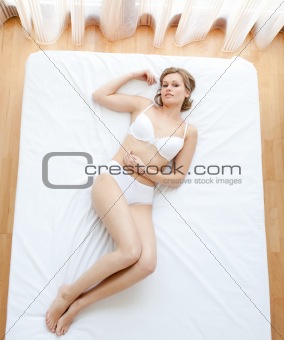 Blond woman in underwear lying on bed