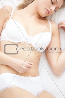 Dreamy woman in underwear lying on bed at home