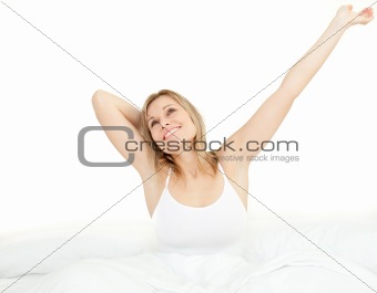 Delighted woman stretching sitting on her bed 
