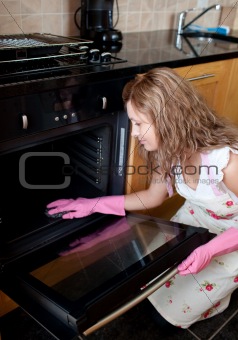 Young woman cleaning the oven 