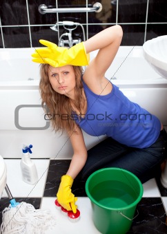 Exhausted woman in a bathroom sitting on the ground