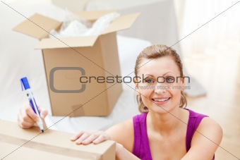 Cute woman writing on boxes using a pen 
