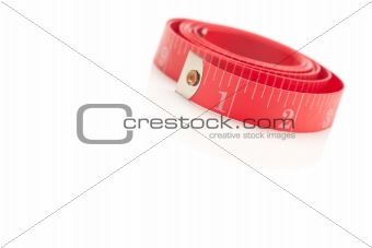 Coiled Red Measuring Tape Isolated on a White Reflective Surface.