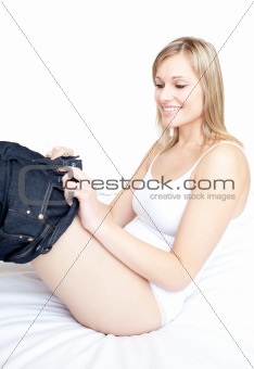 Smiling woman wearing a jeans on a bed