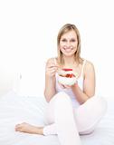 Delighted woman eating cereals with strawberries