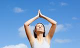 Relaxed woman doing yoga against blue sky