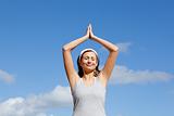 Cheerful woman meditating against a blue sky