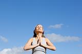 Relaxed woman meditating against a blue sky