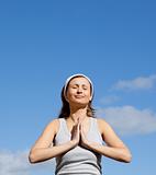 Radiant woman meditating against a blue sky