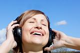 Cheerful woman listenng music outdoors