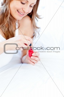 Smiling woman holding a nail varnish at home