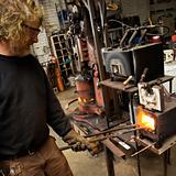 Metalsmith heating metal in forge.