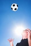 Soccer player or coach and ball against a blue sky