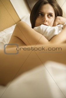 Nude woman in bed.