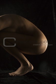 Nude woman crouching.