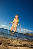 Woman jumping rope on beach.