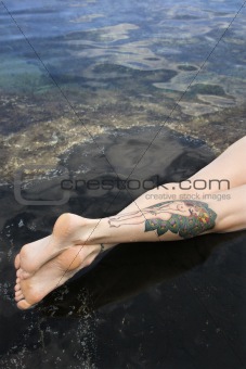 Legs of tattooed woman.