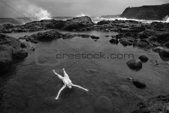 Nude woman floating in coast.